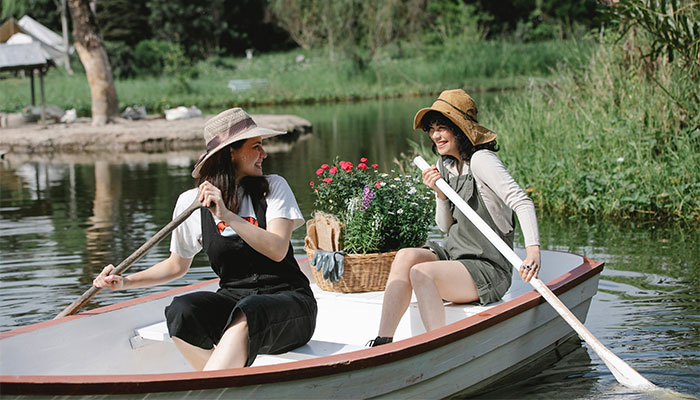Two women smiling and paddling a small boat on a lake after enjoying some Adair County Delta 8 THC Edible Gummies purchased at Simple Garden CBD.