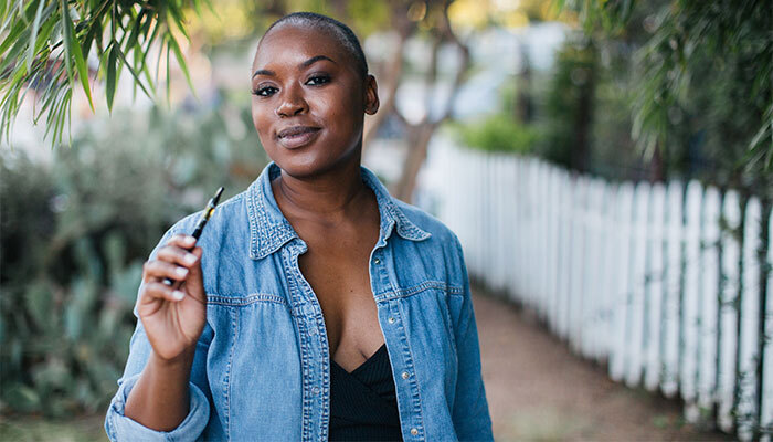 buy-delta-8-vape-pens-pittsboro-indiana-shop-thc-cartridges-46167 Black woman outdoors holding a Pittsboro Delta 8 THC vape pen from Simple Garden CBD