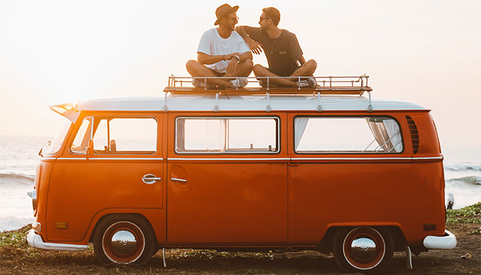 Two friends sitting on orange VW bus after buying Delta 8 gummies in Bath County, Kentucky from Simple Garden CBD.