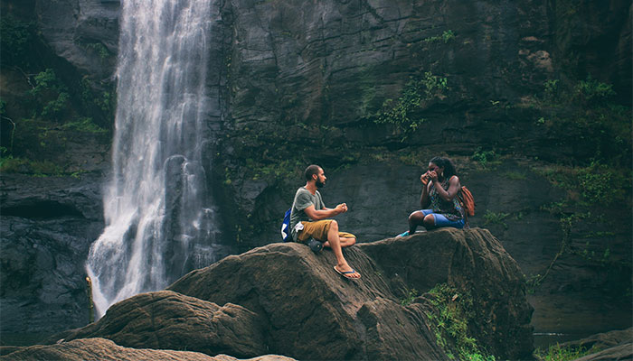 Two people sitting by a waterfall using Alexandria Delta-8-THC products purchased online from Simple Garden CBD.