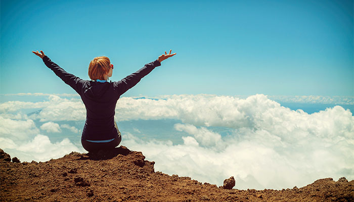 Woman sitting on hilltop overlooking clouds after using Garland Delta 8 products from Simple Garden CBD.