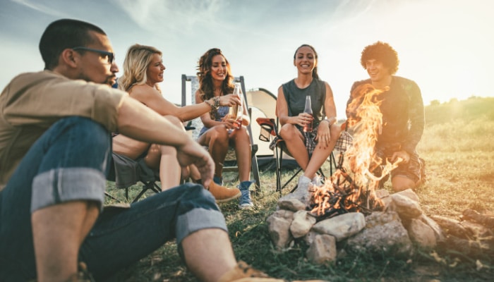 Five friends sitting in chairs and relaxing by a campfire while having Alexandria Delta 9 THC Edibles.