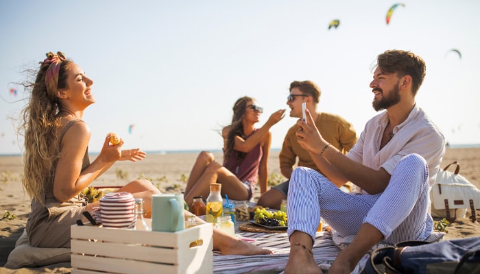 Four friends having a picnic while enjoying THC Edibles near Huntington Beach, California.