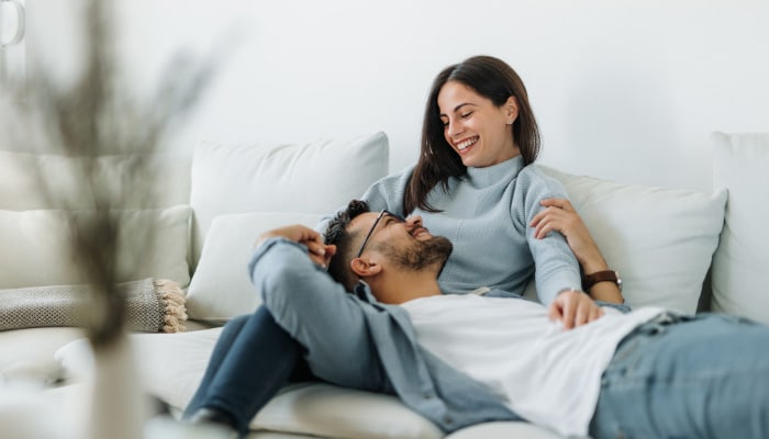 Man and woman relaxing on couch while enjoying Surprise THC Edibles from Simple Garden.