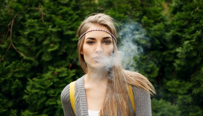 Blonde woman blowing out vapor from a THC vape near Garland, Texas.