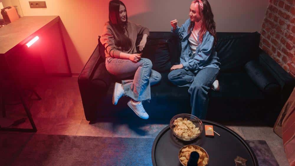 Two women sitting on a couch enjoying Huntsville THCa pre rolls.
