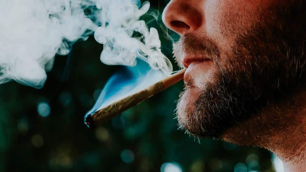 Close up view of a man's face who is smoking a THCa pre-roll near Moreno Valley, California.