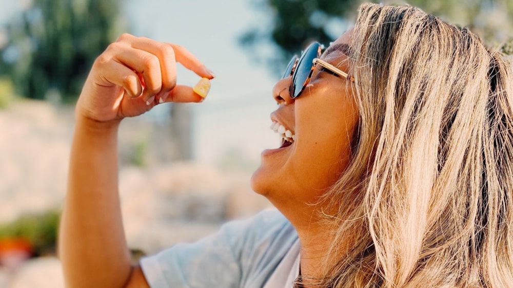 A woman putting a yellow gummy in her mouth, which she purchased as part of the best Black Friday THC deals near Crows Nest, Indianapolis, Indiana.
